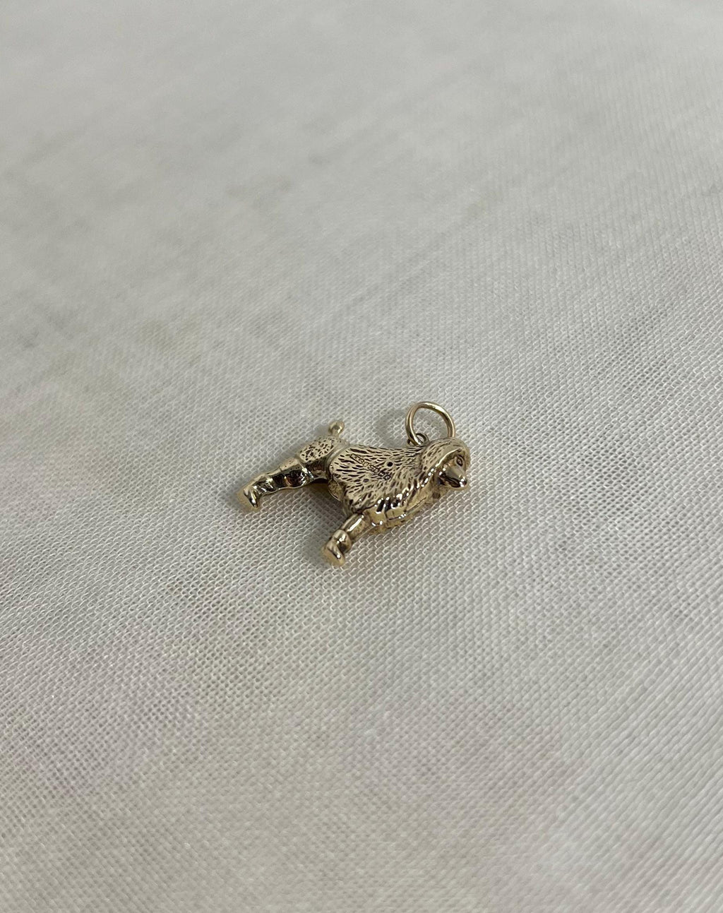 gold dog charm on cream fabric background 