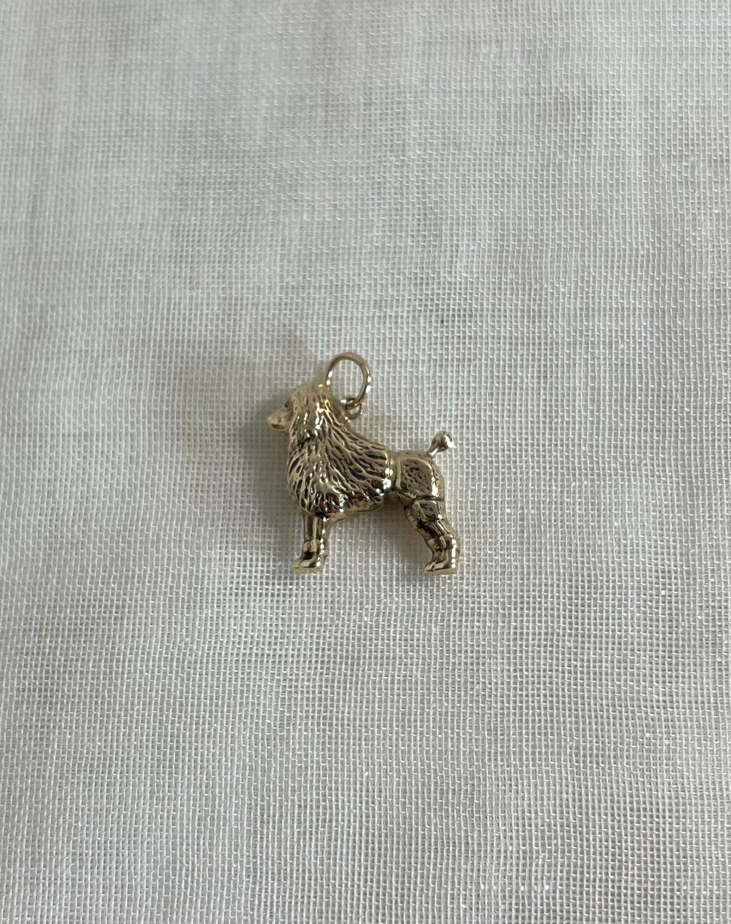 gold dog charm on cream fabric background