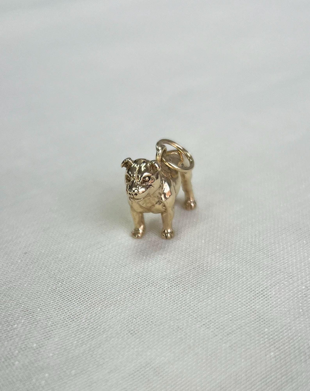 Gold bulldog charm on a white fabric  background