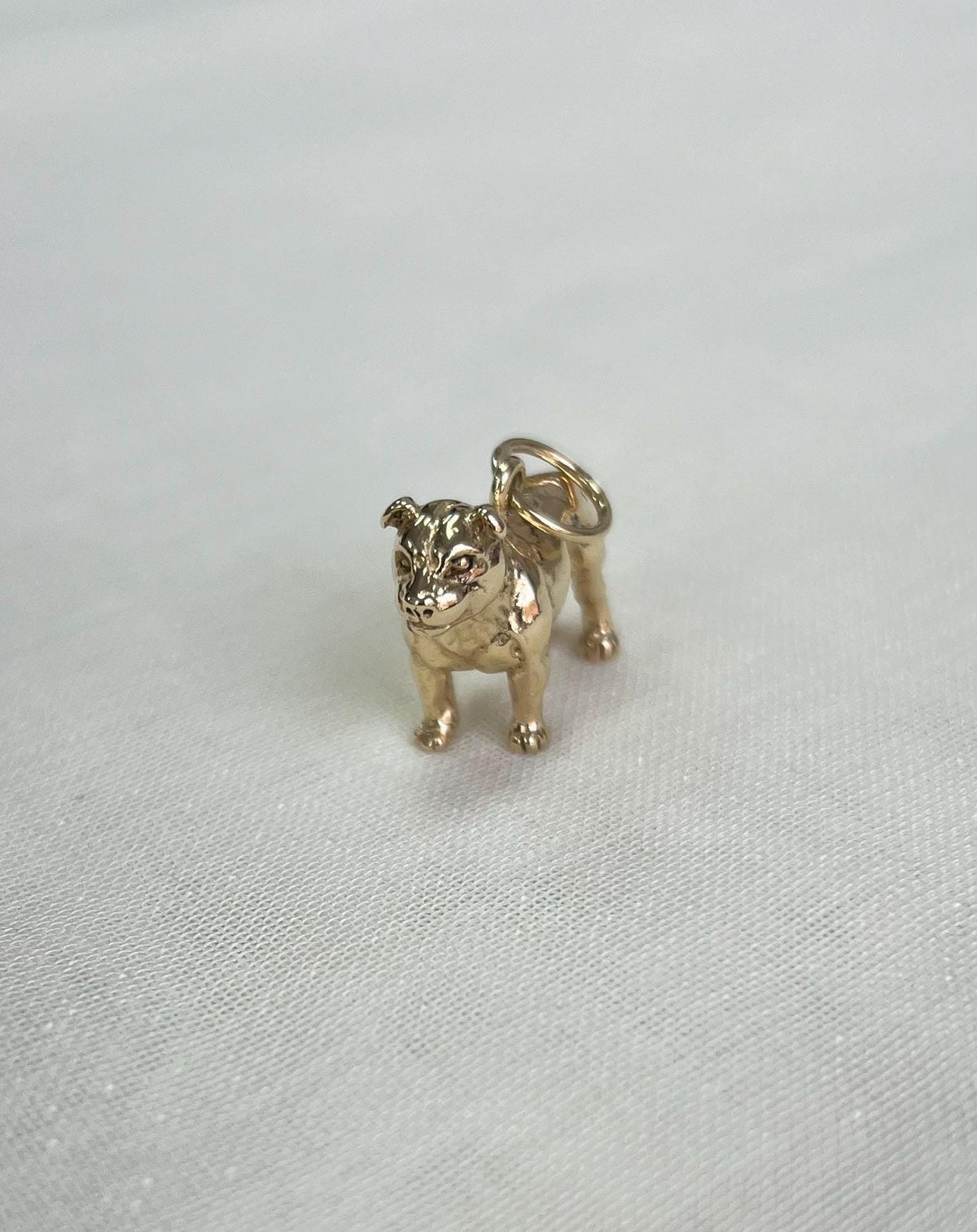Gold bulldog charm on a white fabric  background