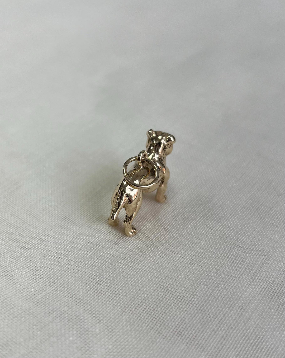 Gold dog-shaped charm on a white fabric  background