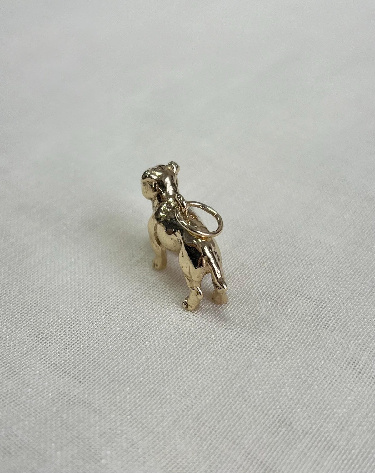 Gold bulldog charm on a light fabric background
