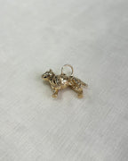 a gold dog charm on white fabric background