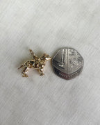gold dog charm next to fifty pence coin on white fabric background