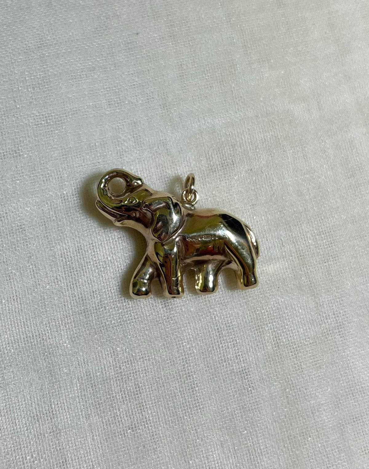 large gold elephant charm on white fabric background