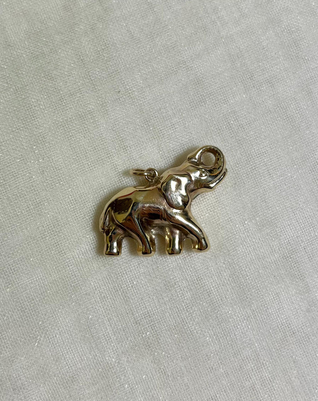 gold elephant charm on white fabric background