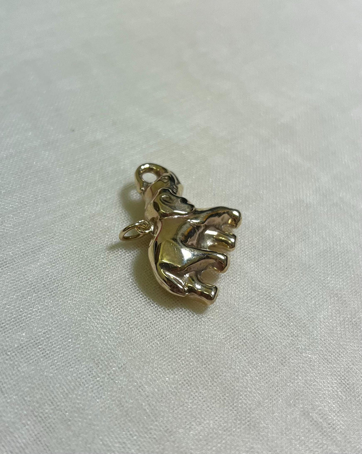 large gold elephant charm on white fabric background