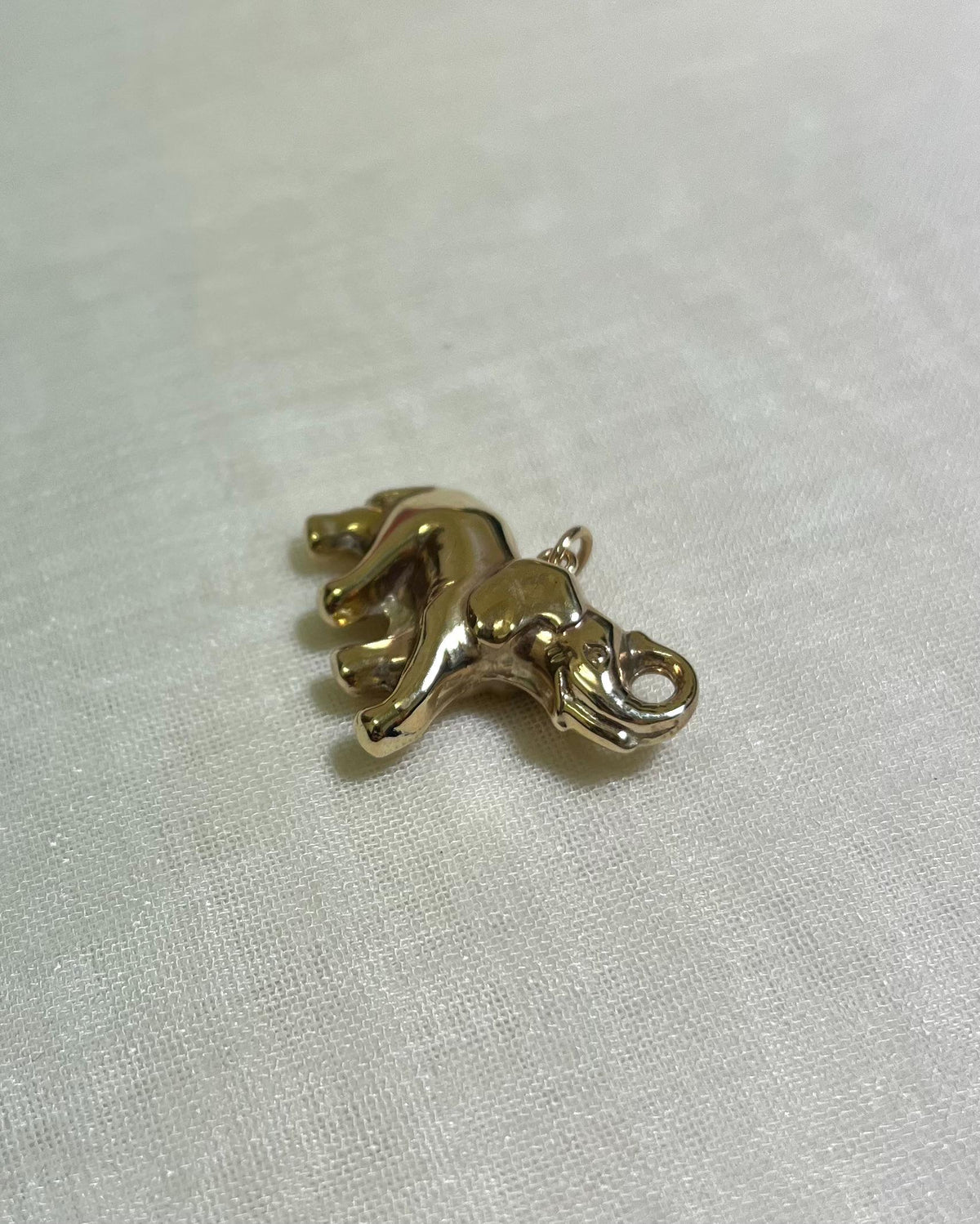 gold elephant charm pn white fabric background