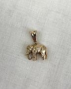 Gold elephant pendant on a cream fabric background