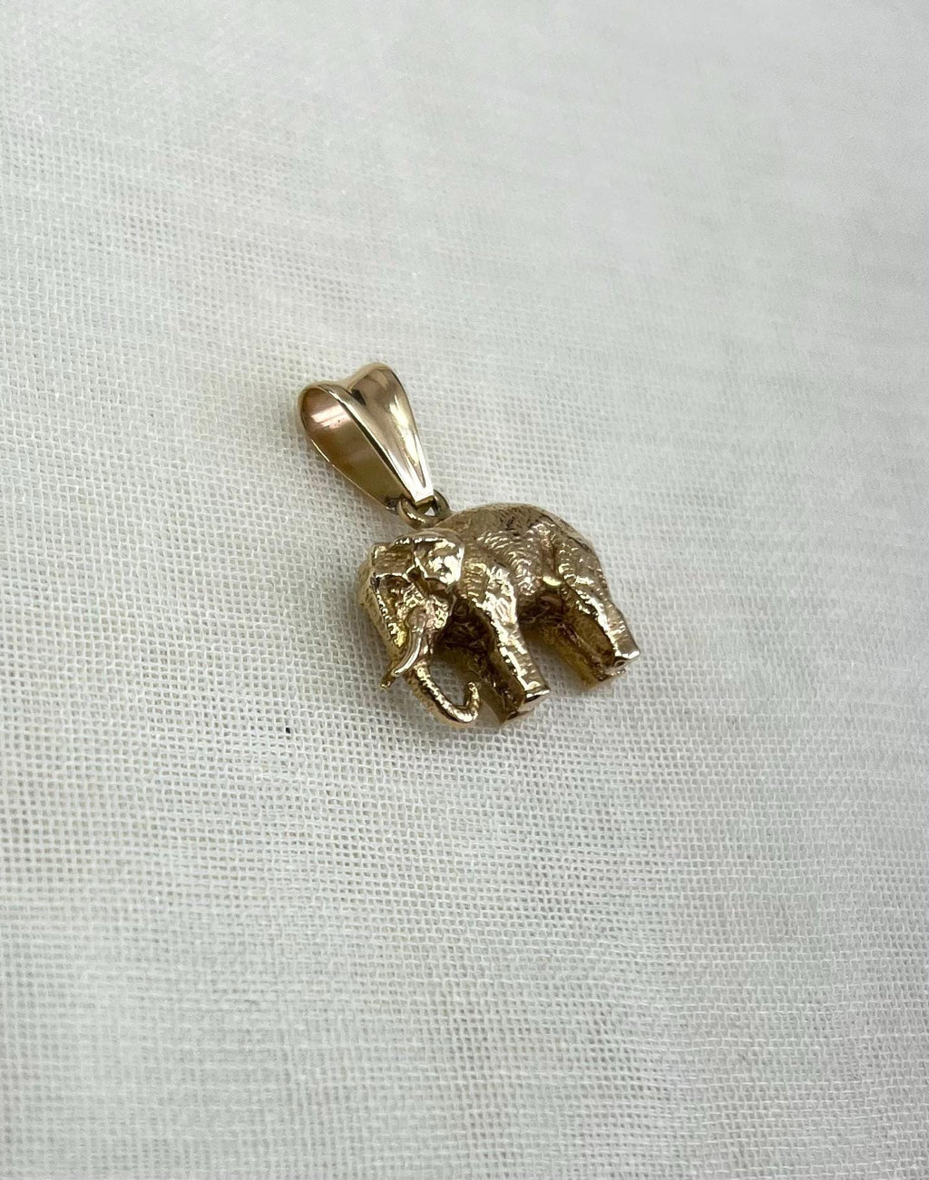 Gold elephant pendant on a light fabric background