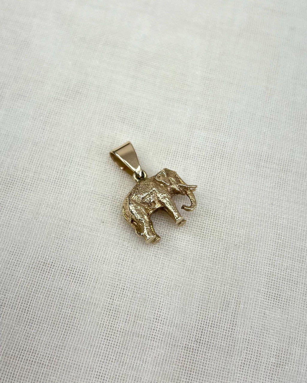 Gold elephant pendant on a light fabric background