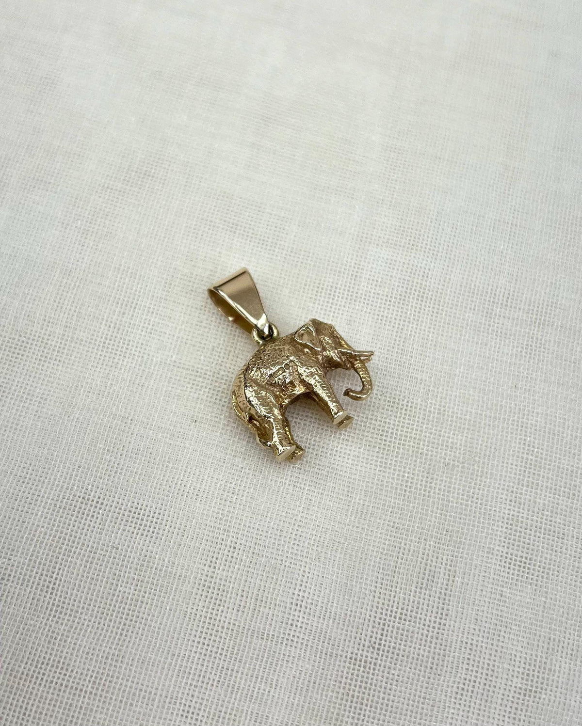 Gold elephant pendant on a light fabric background