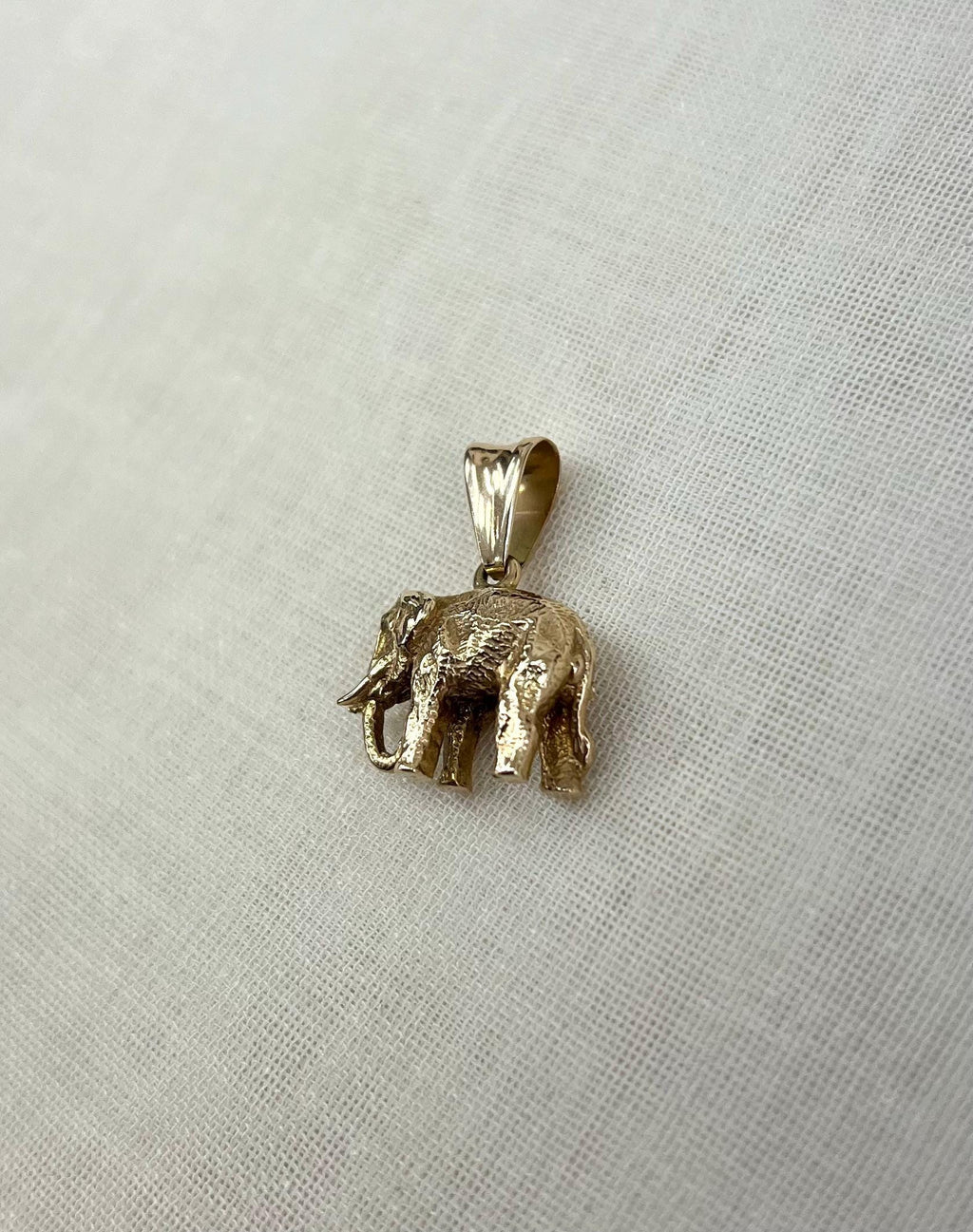 Gold elephant pendant on a light fabric background