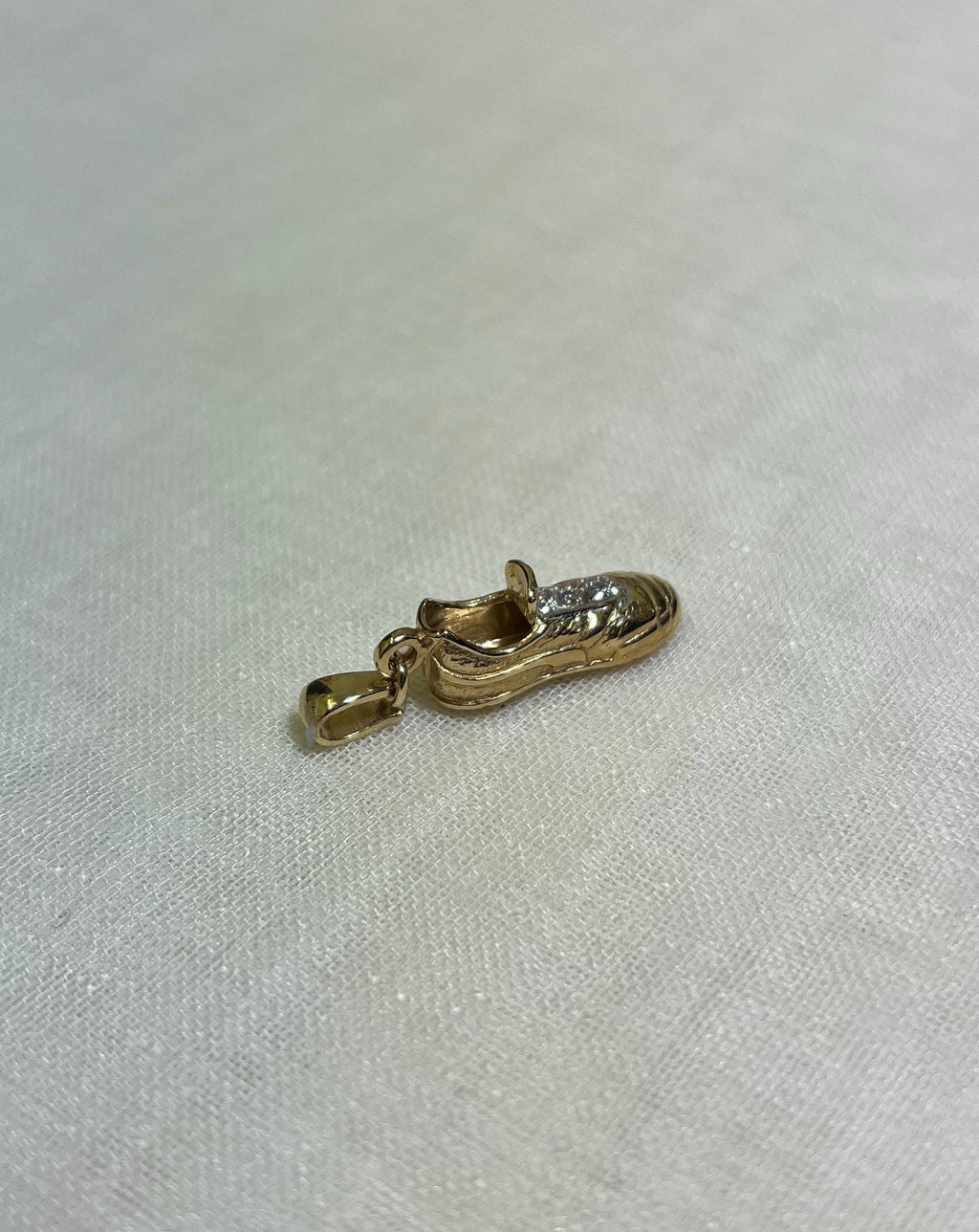 Gold shoe charm on a light fabric background