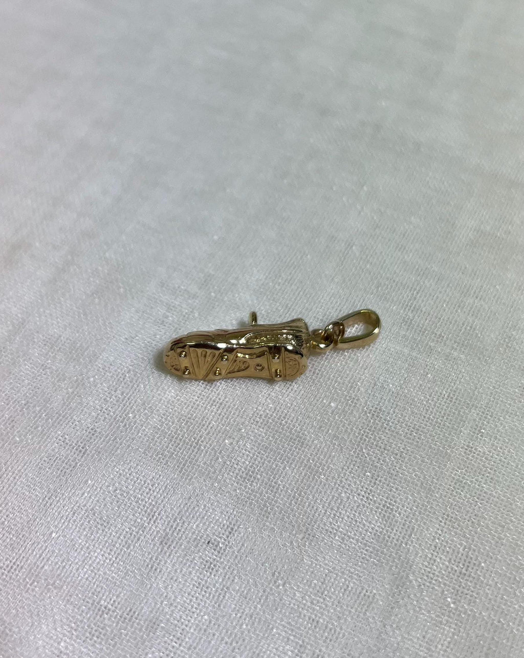 bottom of gold boot pendant on white fabric background 