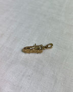 bottom of gold boot pendant on white fabric background 