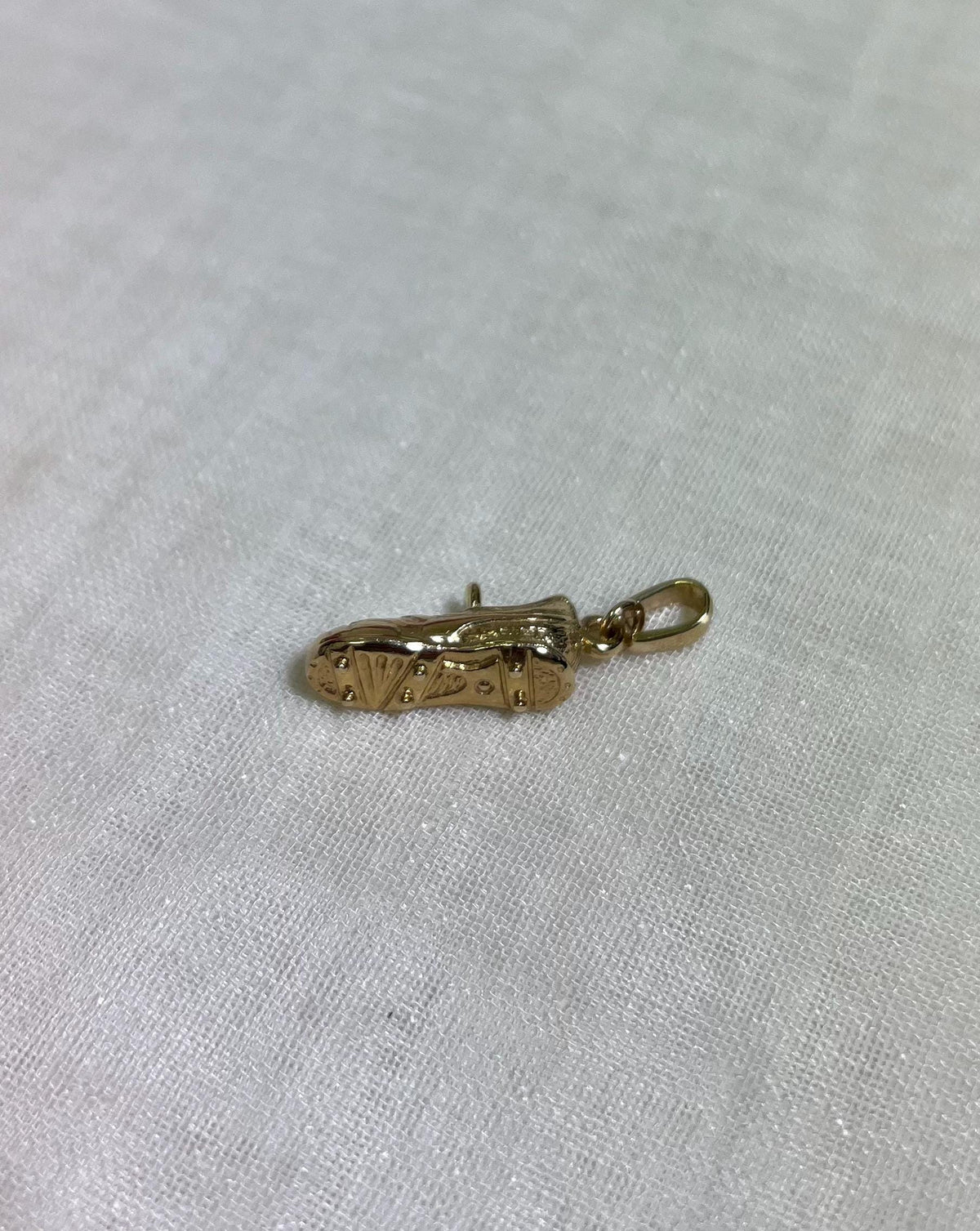bottom of gold boot pendant on white fabric background 