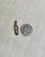 gold shoe pendant with clear gemstones, next to ten pence coin for scale, resting on white fabric background