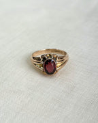 Gold ring with a red gemstone on a white fabric background