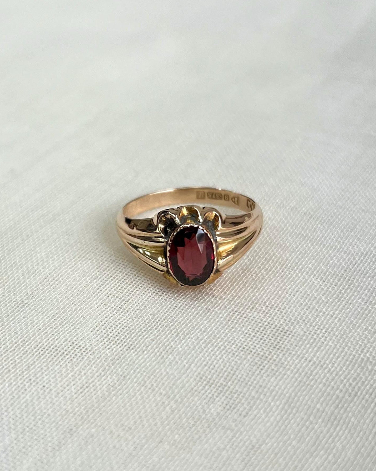 Gold ring with a red gemstone on a white fabric background