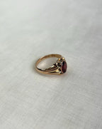 Gold ring with a red gemstone on a light gray background