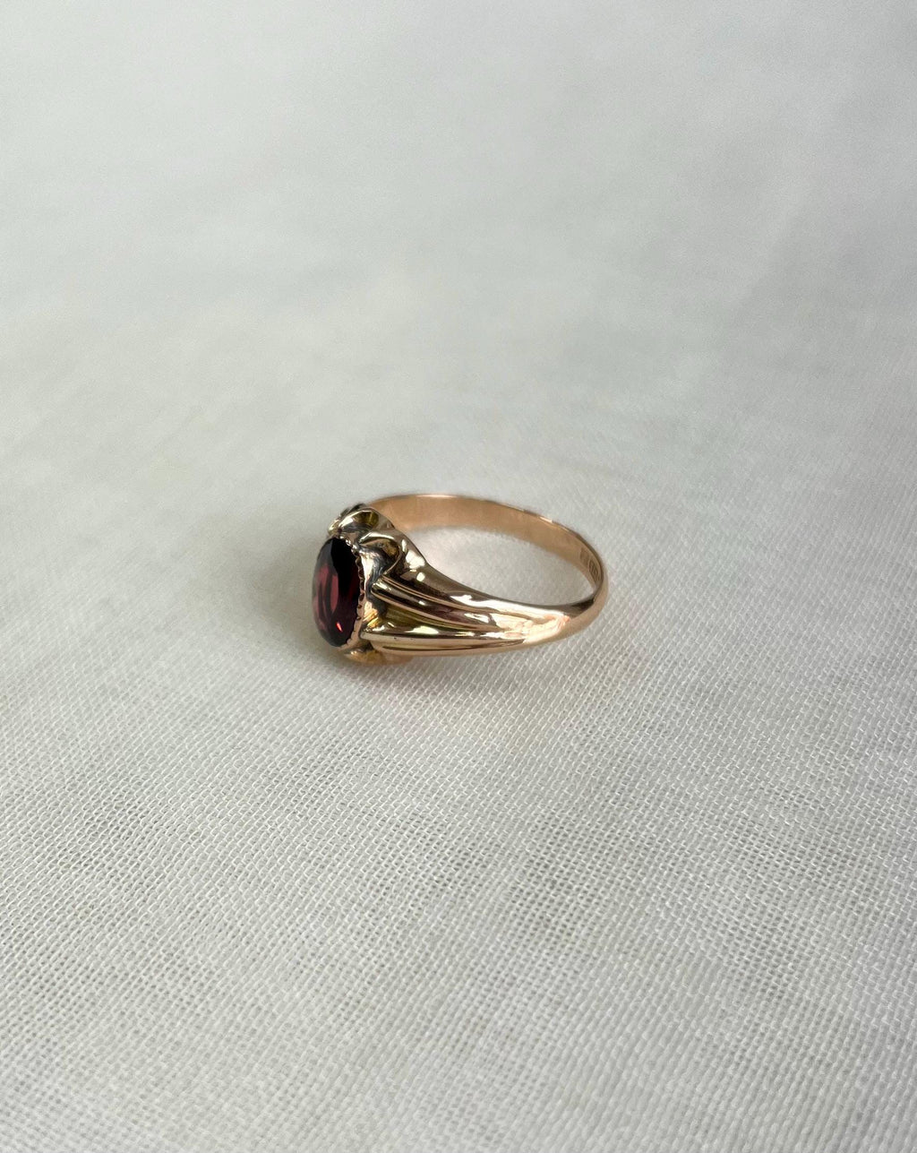 Gold ring with a red gemstone on a light gray background