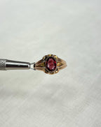 Gold ring with a red gemstone on a white background