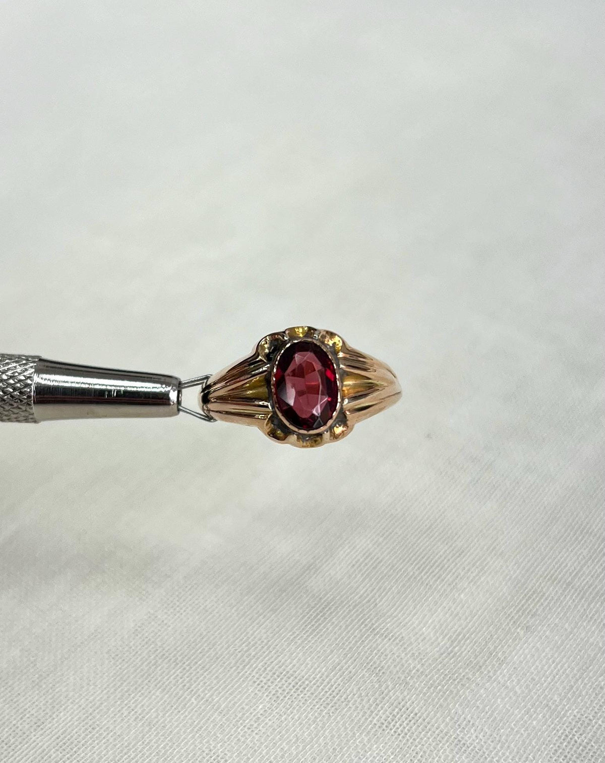 Gold ring with a red gemstone on a white background