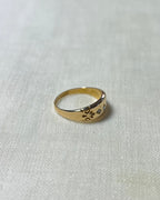 a vintage gold ring with pattern engraving, resting on white fabric background 