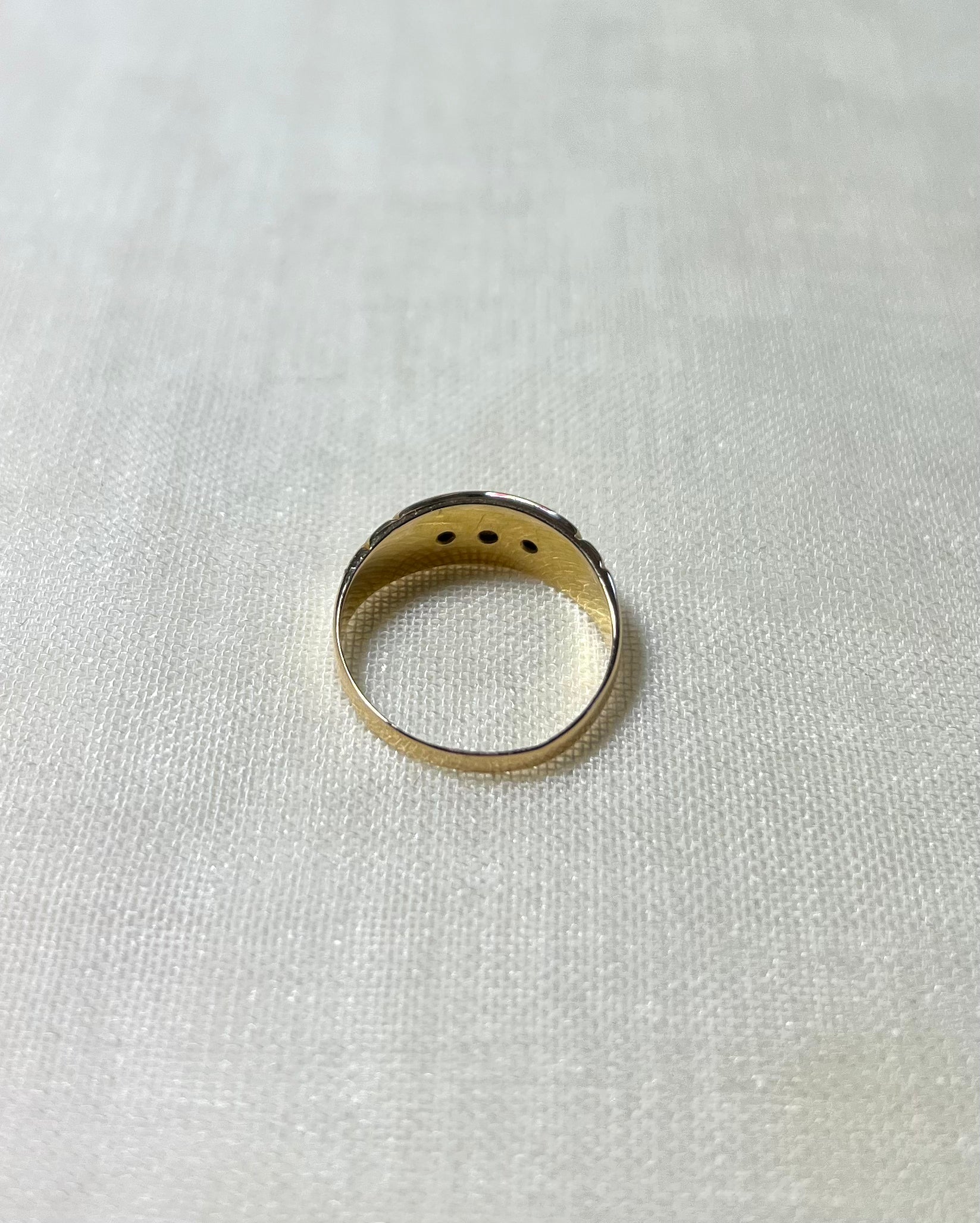 back view of gold ring resting on white fabric background 