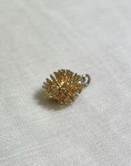 gold hedgehog charm resting on cream fabric background 
