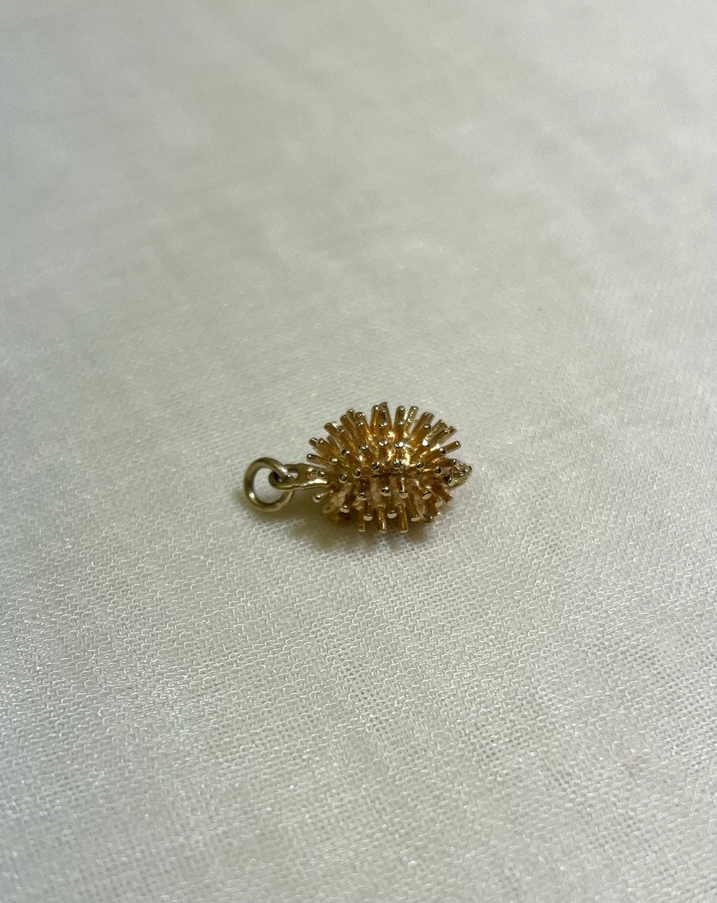 gold hedgehog charm on cream fabric background