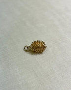 gold hedgehog charm on cream fabric background