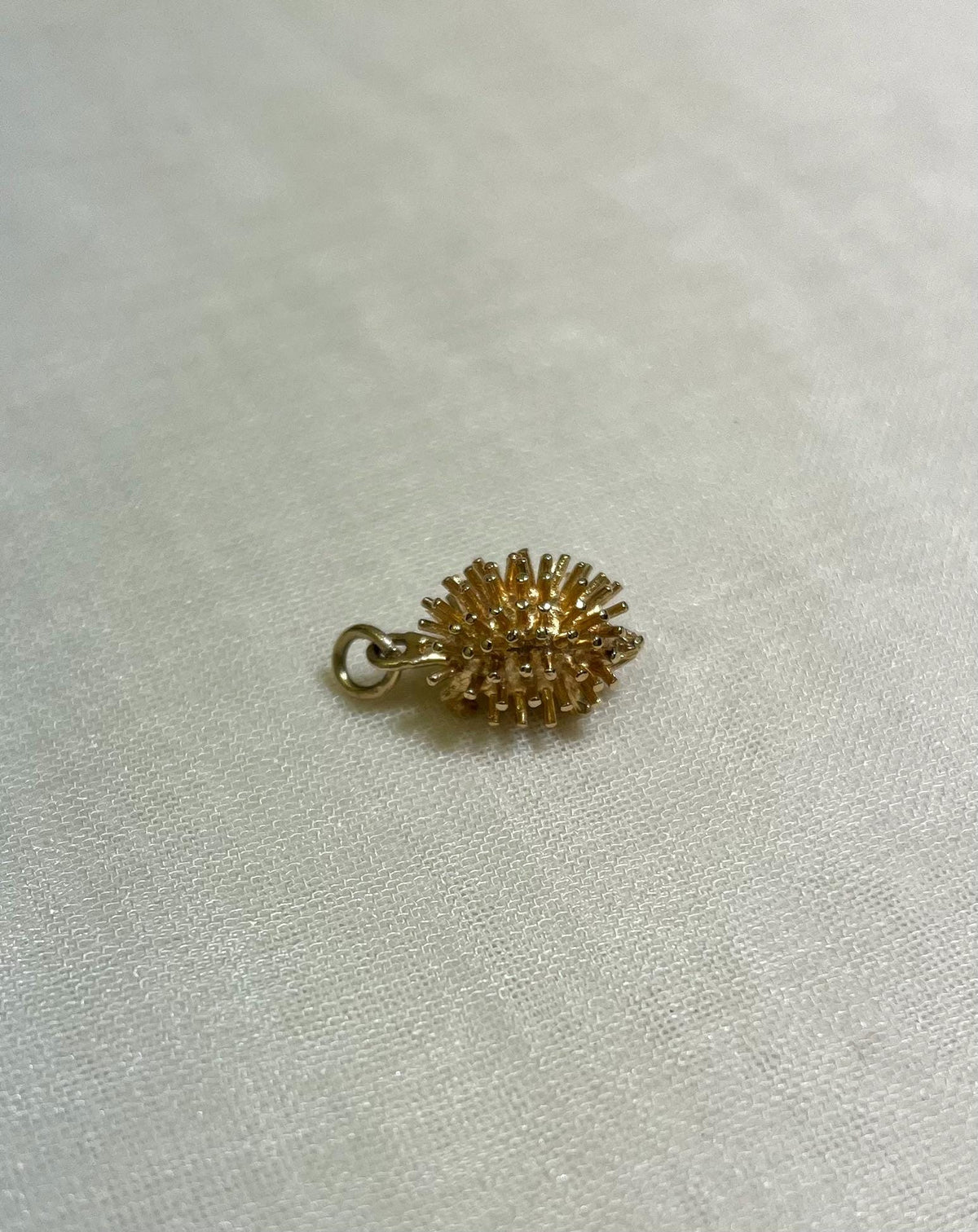 gold hedgehog charm on cream fabric background
