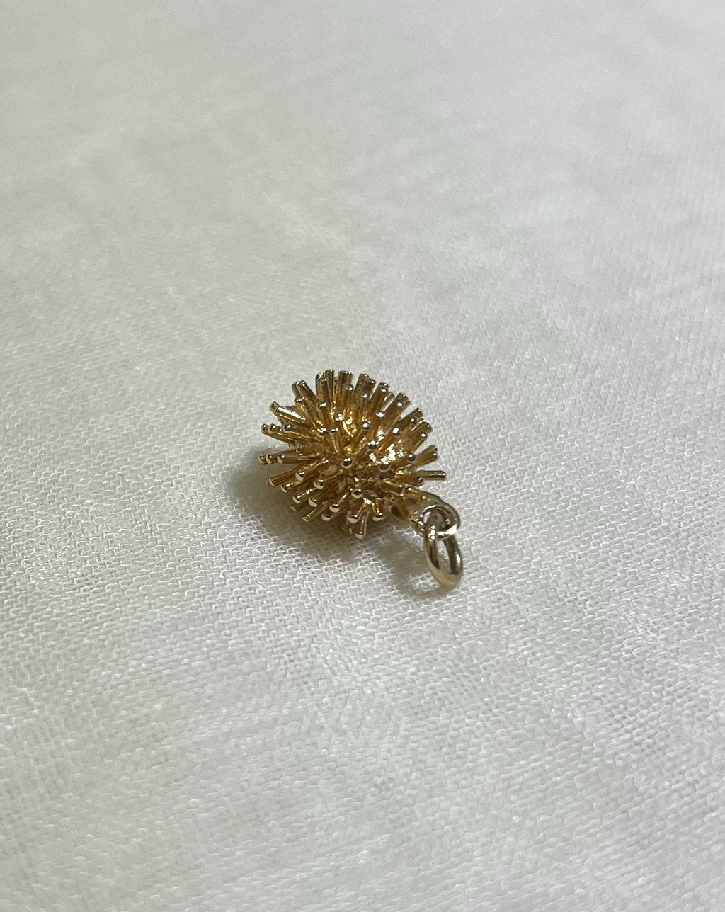 gold hedgehog charm on cream fabric background