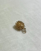 gold hedgehog charm on cream fabric background