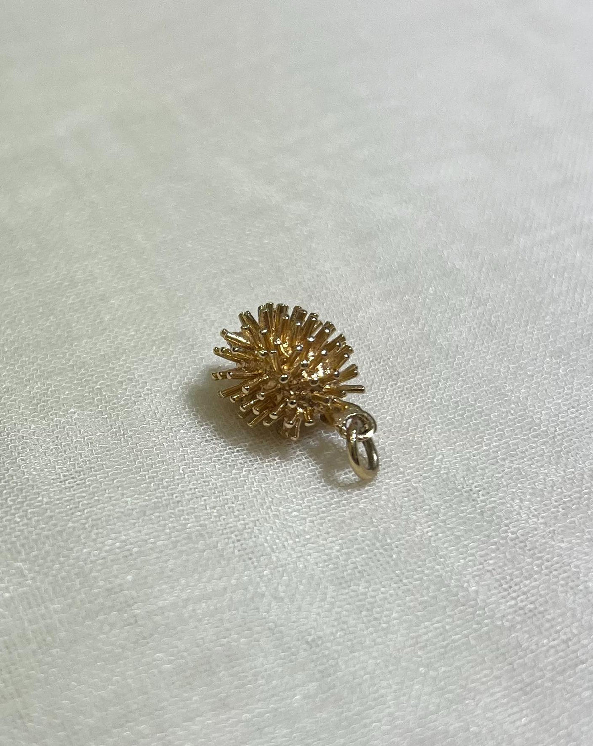gold hedgehog charm on cream fabric background