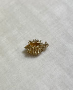 gold hedgehog charm side view, on cream fabric background 