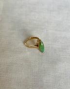 Gold ring with a green gemstone on a light beige fabric background