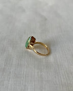 side view of green stone gold ring on light beige fabric background 