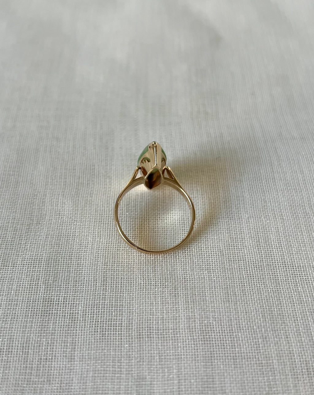 back view of gold ring on light beige fabric background 