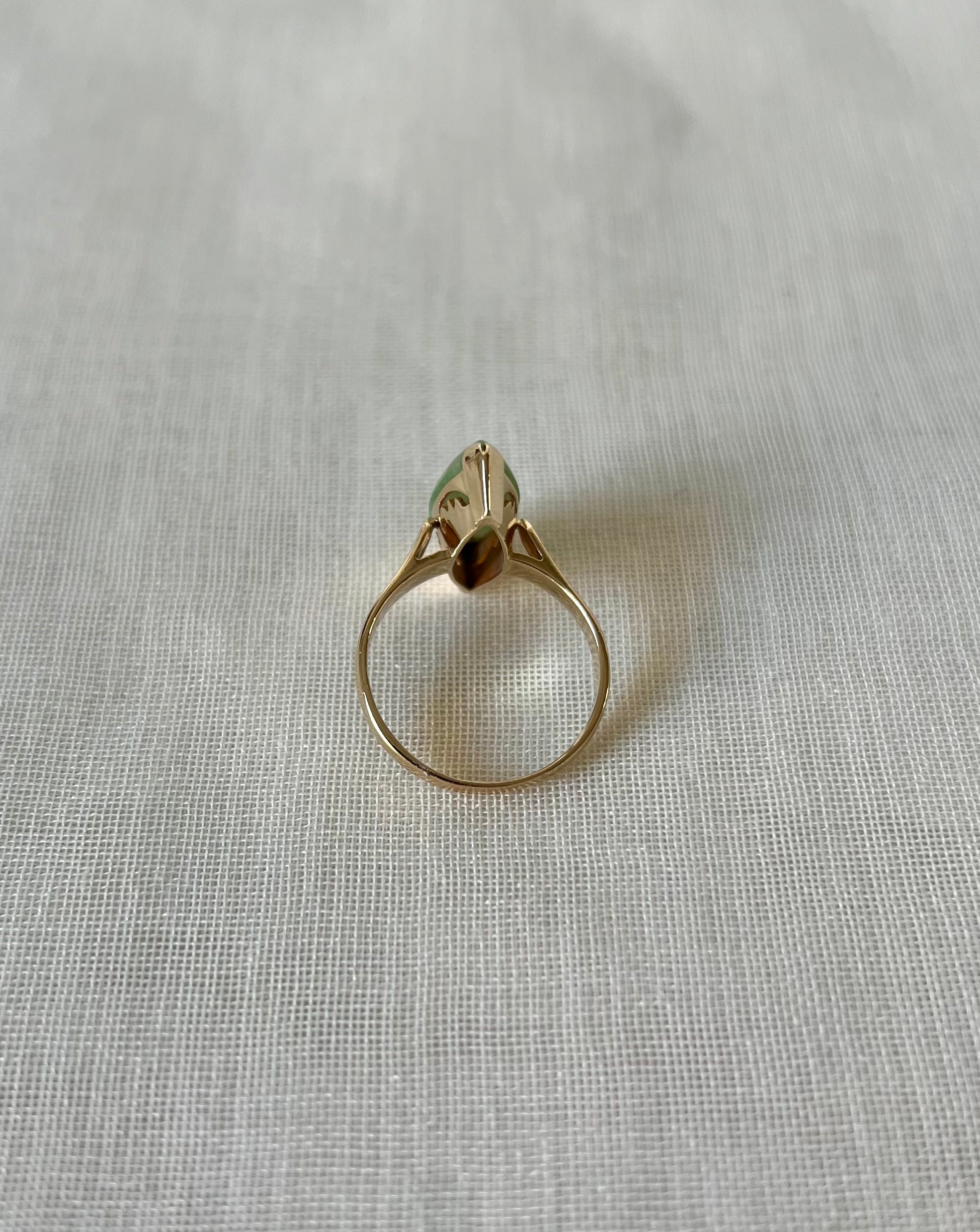 back view of gold ring on light beige fabric background 