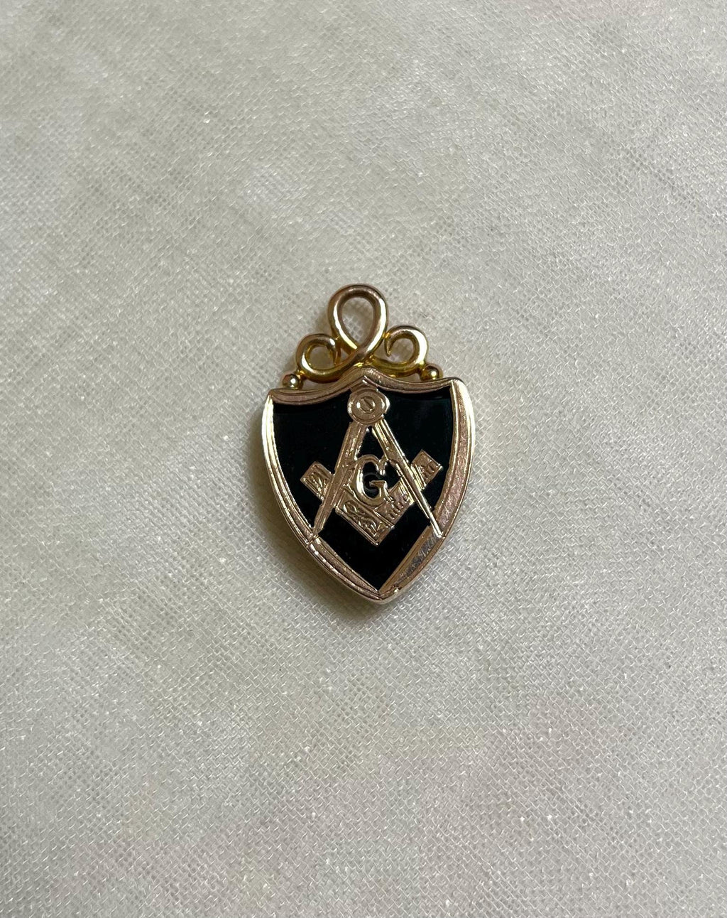 gold Masonic pendant on a white fabric background