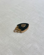 side view of gold shield pendant set with dark bloodstone, on white fabric background 