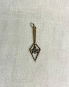 Gold pendant with geometric design on a light fabric background