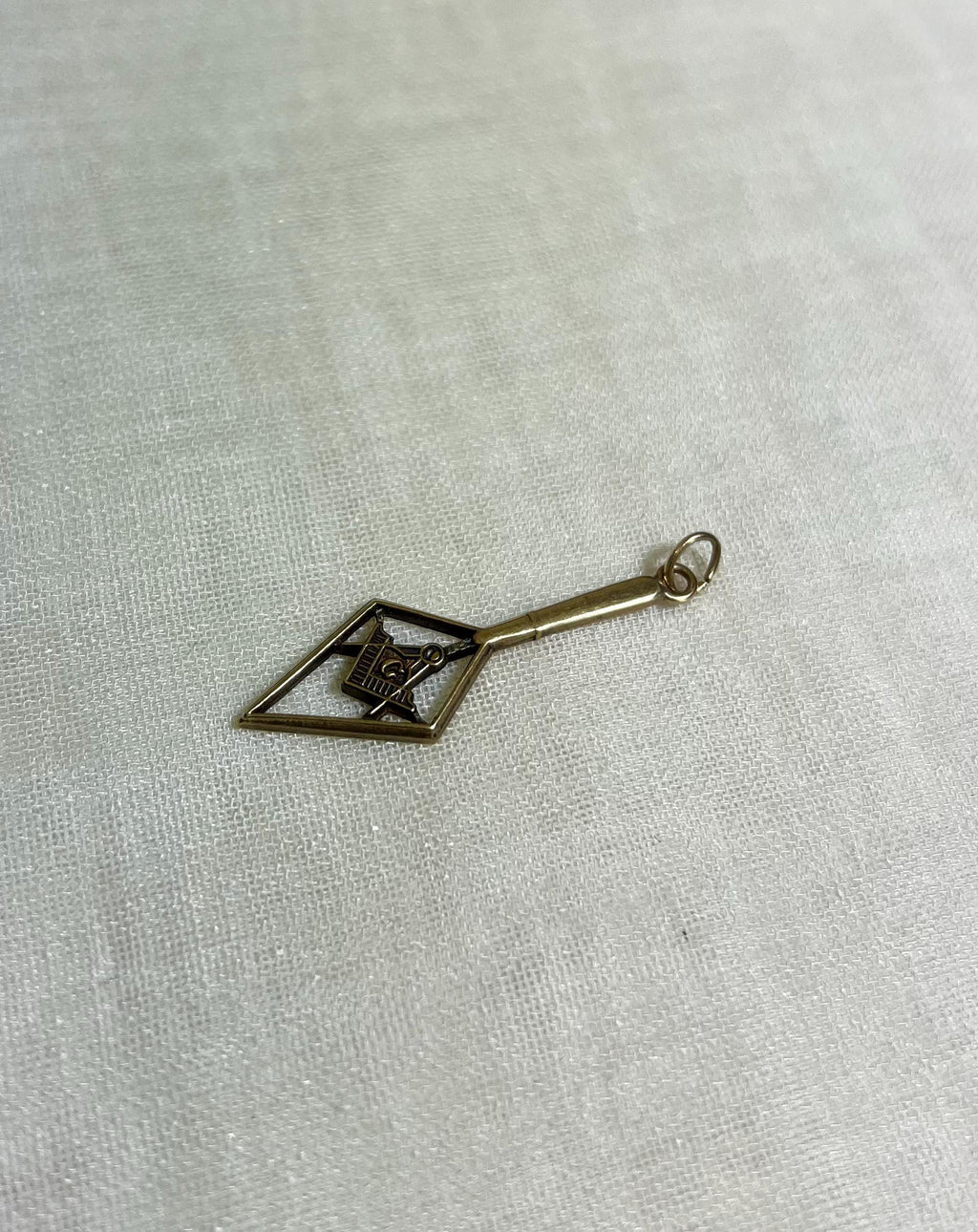Gold charm with geometric design on a light fabric background