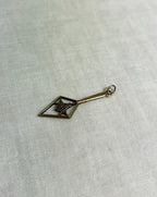 Gold charm with geometric design on a light fabric background