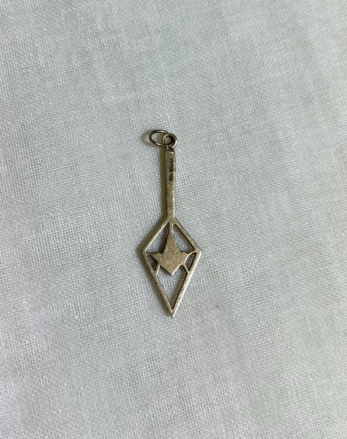 back view of gold pendant on white fabric background 