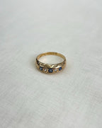 gold band set with blue sapphires and diamonds, resting on white fabric background 