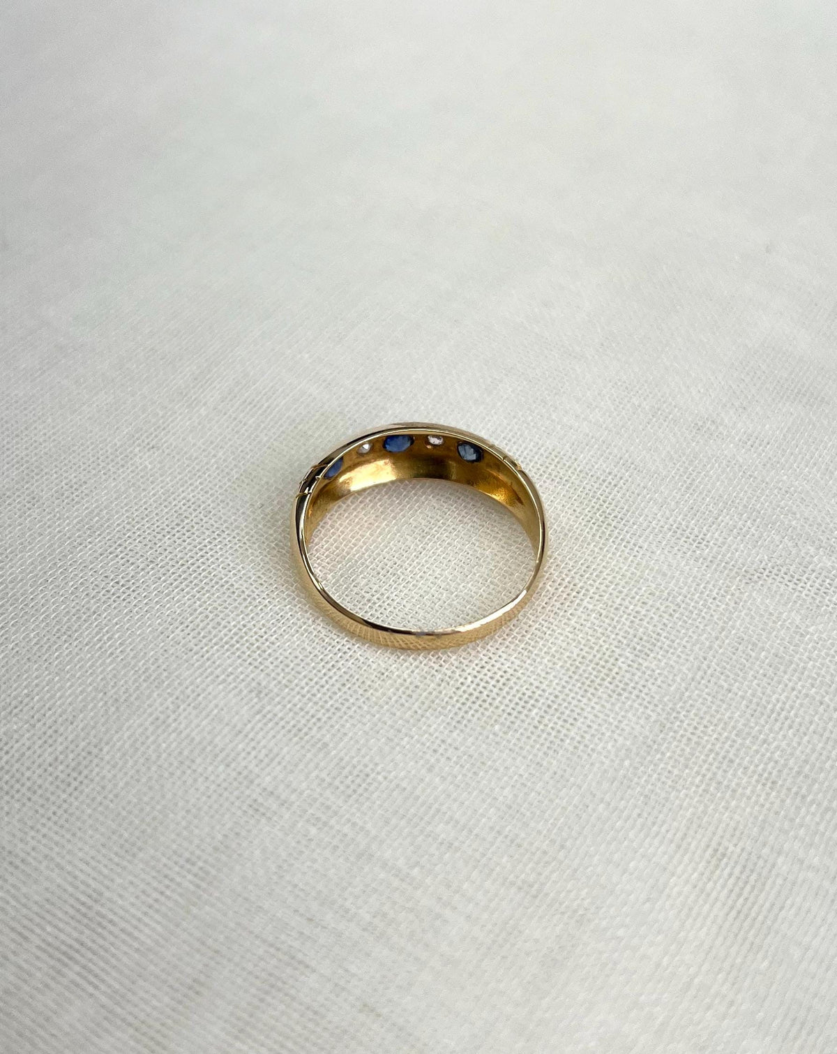 back view of gold ring resting on white fabric background 